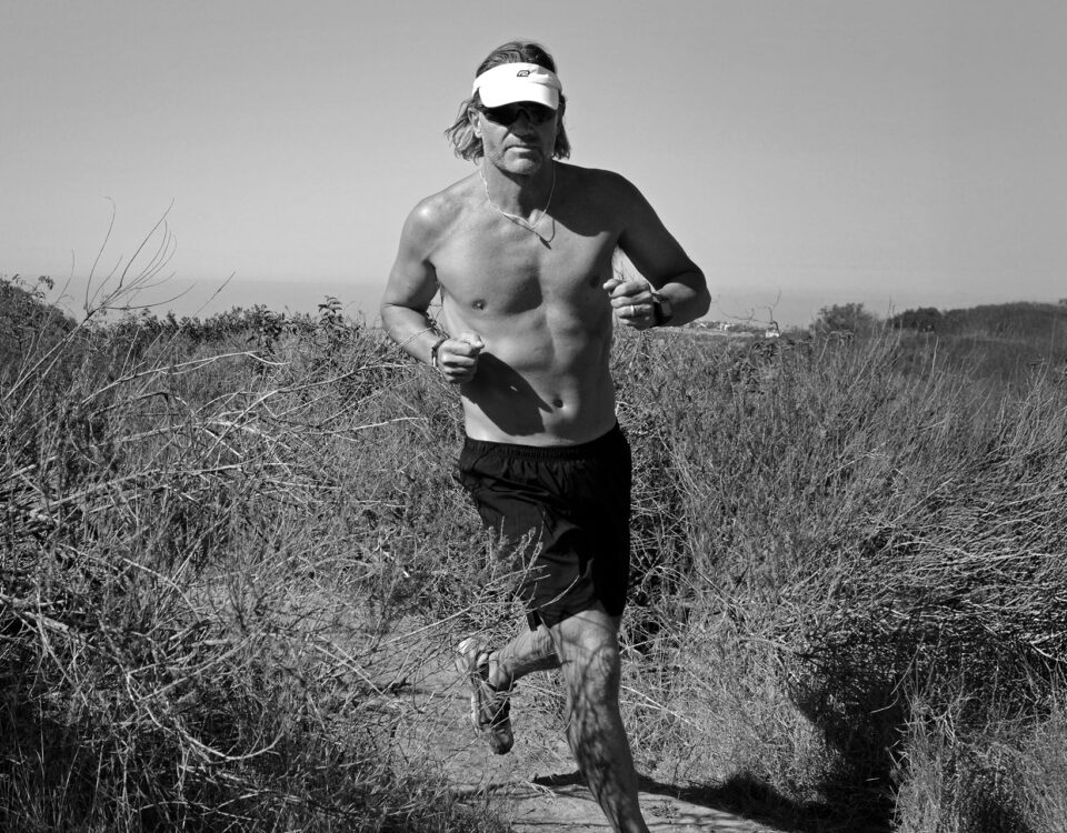 Craig running on a forest trail, reflecting on the cardiovascular risks of long-term endurance training and the importance of heart screening for athletes.