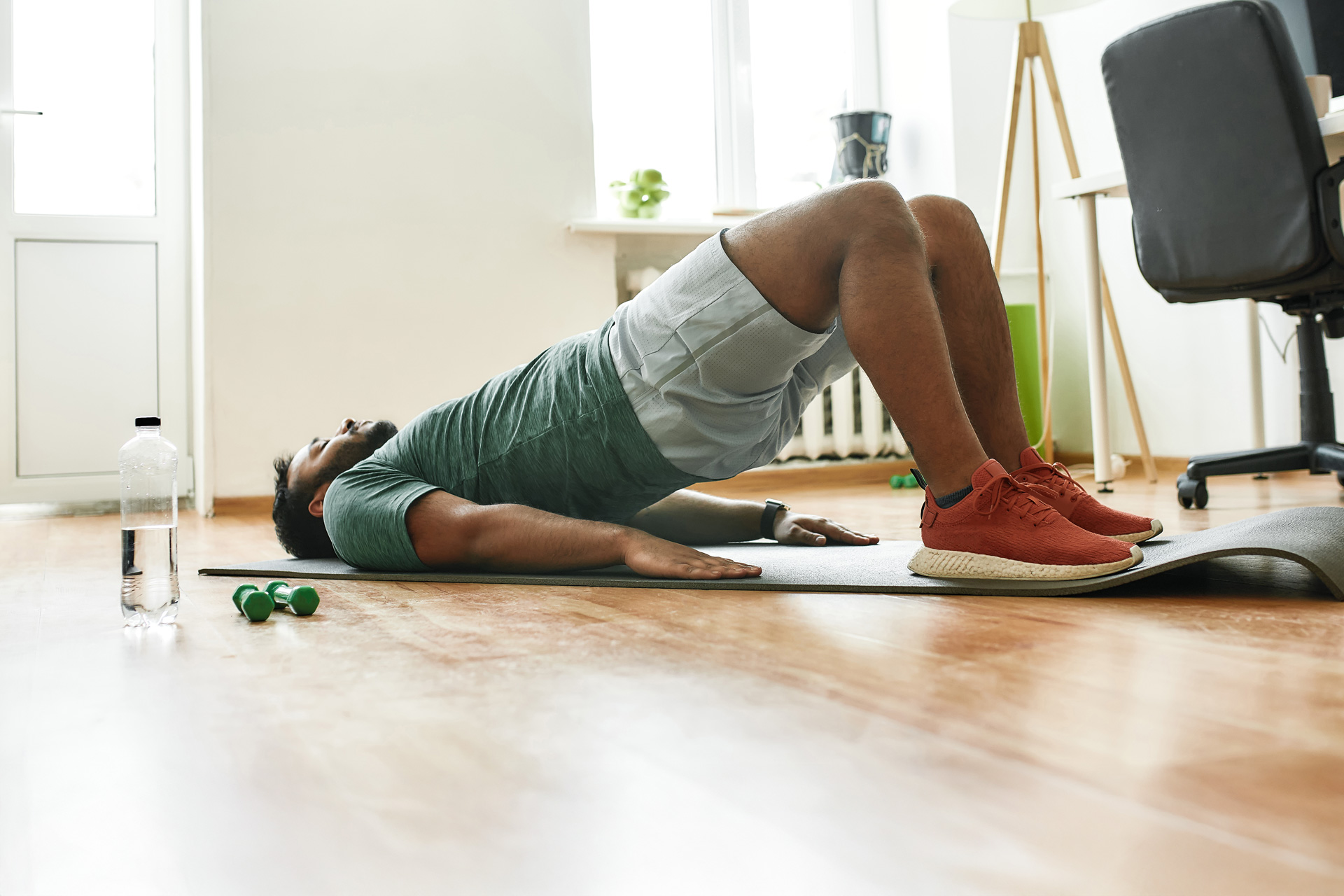 Man performing a glute bridge on a yoga mat—an exercise often used to activate pelvic floor muscles during Kegel routines for men’s sexual and vascular health.
