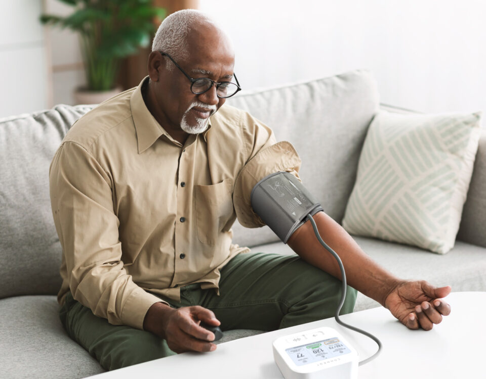 Man measuring his blood pressure at home while seated on a couch.
