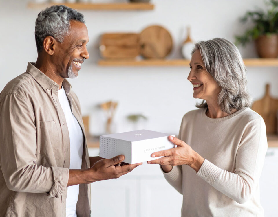 A woman passes a CONNEQT Pulse arterial health monitor to a man.