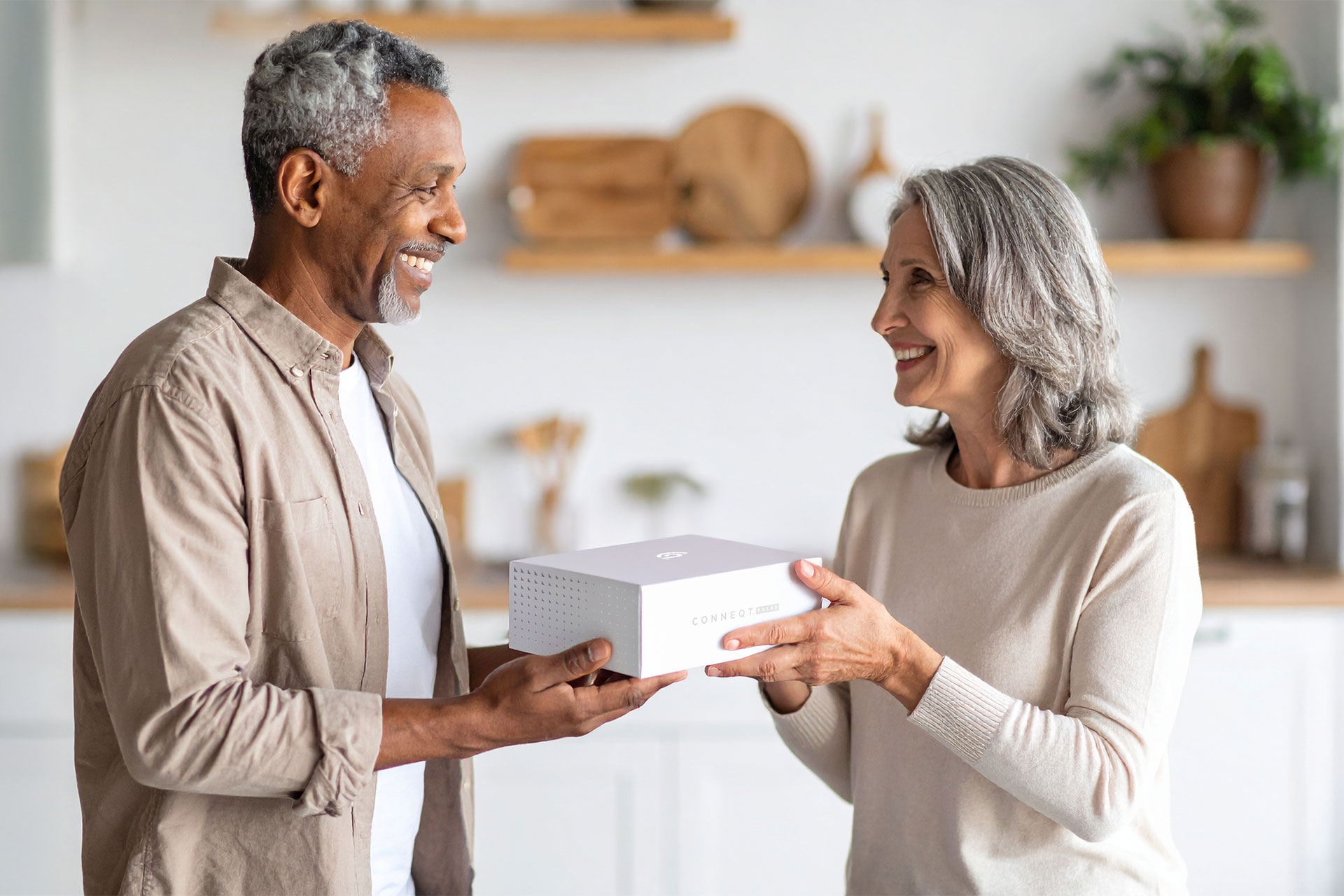 A woman passes a CONNEQT Pulse arterial health monitor to a man.