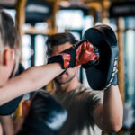 A woman boxing with a trainer to improve her arterial health in her 30s.
