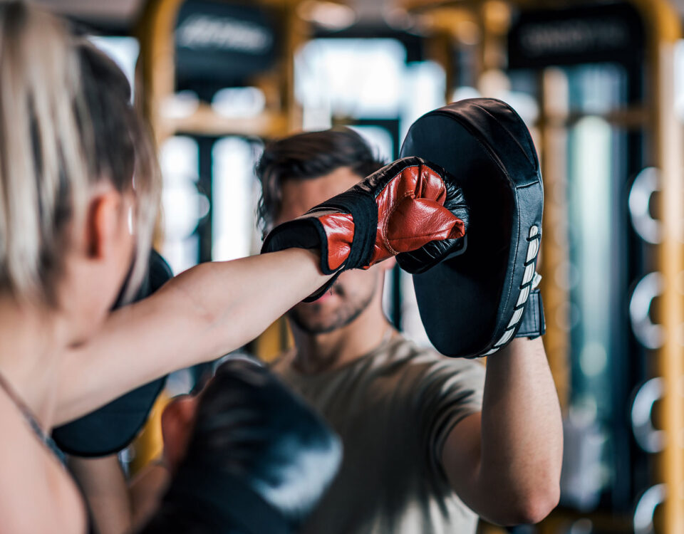 A woman boxing with a trainer to improve her arterial health in her 30s.