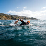 Swimmer in open water pondering how much exercise is too much.