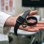 A clinician holding several blood pressure wearables in one hand.