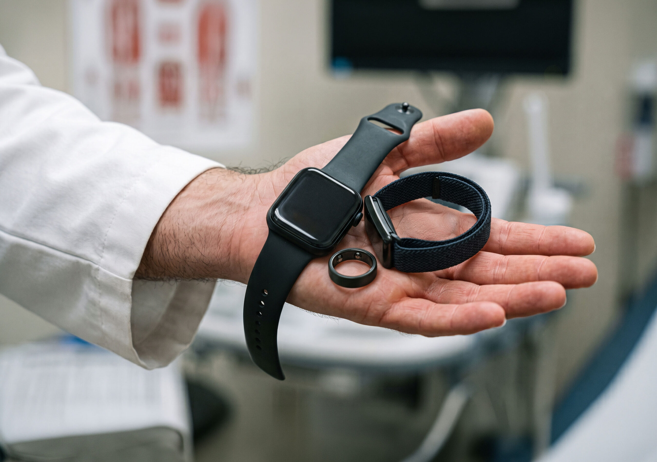 A clinician holding several blood pressure wearables in one hand.